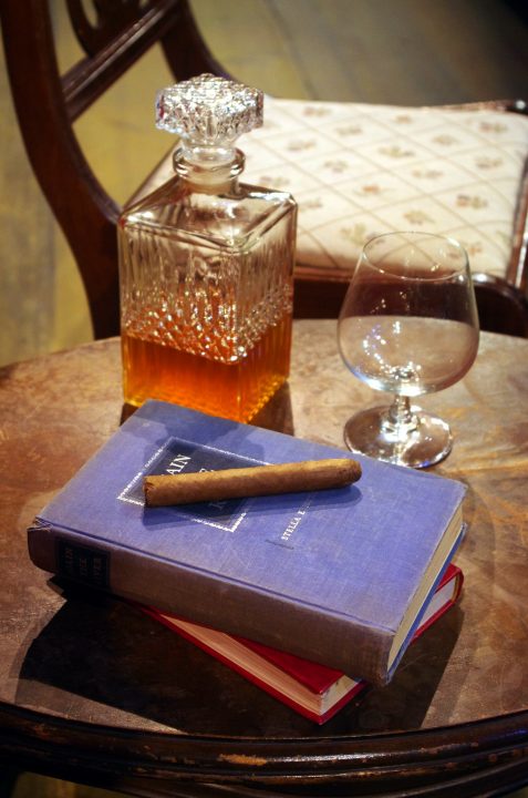 Brandy, cigar and books on an empty chair